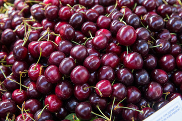 Close up of pile of ripe cherries with stalks and leaves. Large collection of fresh red cherries. Ripe cherries background.