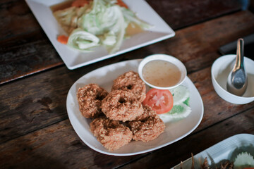 Fried shrimp cake,Thai food name is Tod Mun Goong eat with sweet sauce served on white dish in restaurant.