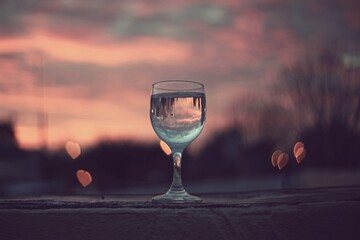 Drink with water on terrace at sunrise with hearts bokeh and pink sky