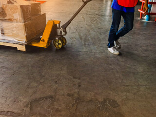 Worker driving forklift loading and unloading shipment carton boxes and goods on wooden pallet from container truck to warehouse cargo storage in logistics and transportation industrial 