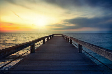 Fototapeta premium Holzsteg im Meer bei Sonnenuntergang