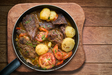 Homemade lunch. Pieces of meat in the iron pan. Isolated on wooden background.Copy space.