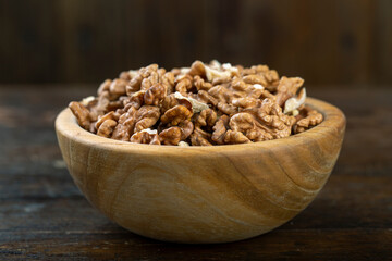 Walnut in wood bowl on wooden background with copy space