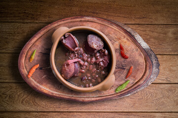 Feijoada. Traditional Brazilian food. Ceramic bowl isolated on rustic wooden background. Top view.