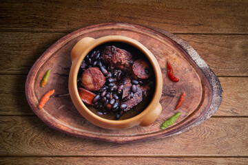 Feijoada. Traditional Brazilian food. Ceramic bowl isolated on rustic wooden background. Top view.