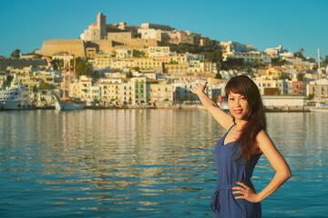 Fototapeta na wymiar Asian woman standing in front of old town in Ibiza, Spain. Summer vacation concept
