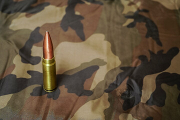 one bullet on khaki background. dangerous tools of war