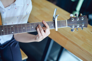 Woman hands playing guitar with a capo