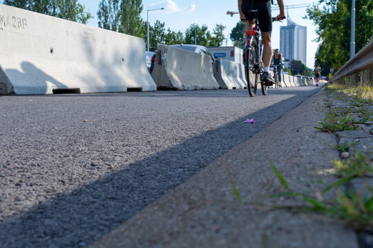 People are biking on a controversial so-called "Pup-Up Cycling Road" (Pop-Up Radweg) by using a part of a road as a temporary cycling path.