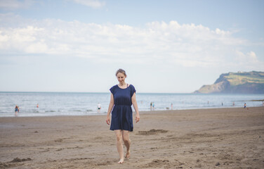 a woman in a dress walk quietly on the beach
