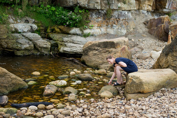 young woman on the water's edge among the stones
