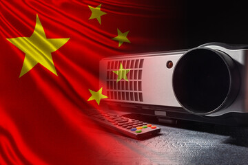 Media projector with remote control on the background of the Chinese flag. Watching the news from China. A film about China. Training video about the economy of the Republic of China.