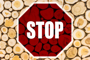 A STOP sign on the background of the cut down trees. The requirement of rational use of natural...