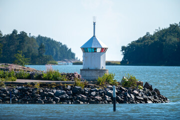 A small lighthouse standing on top of a breakwater made out of rocks and stones.