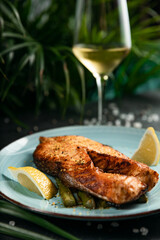 Grilled salmon and asparagus on plate with glass of white wine
