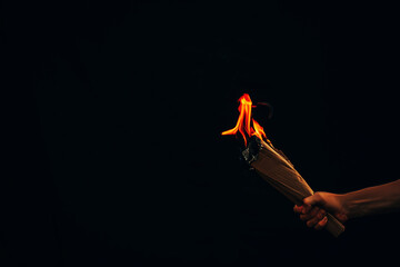 Fototapeta na wymiar Man hand holding white burned paper. Fire. Dark background. Man hand. Male. 