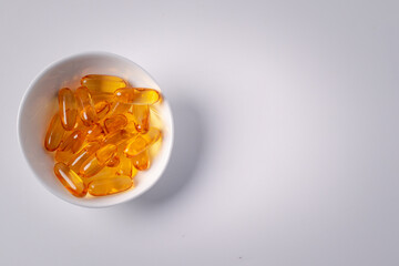 Cod liver oil in white ceramic cup on white background