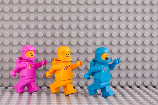 Tambov, Russian Federation - June 04, 2020 Three The LEGO Movie 2 astronaut minifigures going one after another on gray baseplates background.