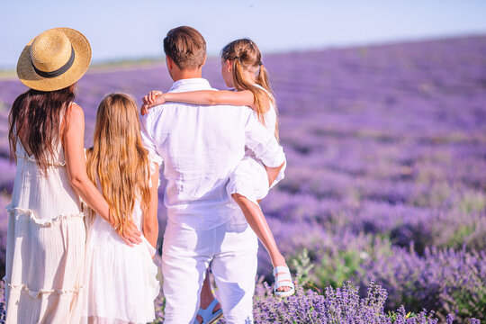 Family In Lavender Flowers Field At Sunset In White Dress And Hat