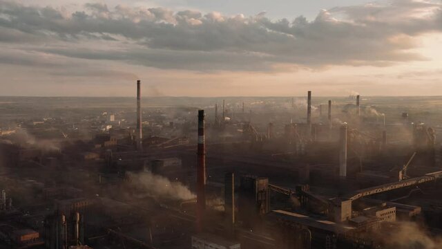 Drone shot of industrial zone with thick smog and burning fossil fuels. Factory zone pan shot from left to right, air pollution and soot in many factory chimneys in city area