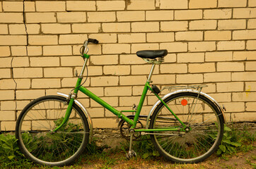 Fototapeta na wymiar Green old retro Russian folding bicycle on a background of white bricks