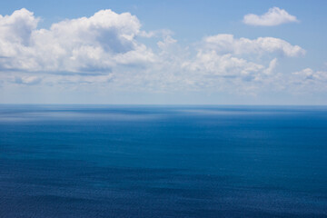Obraz premium Photo of a bright blue sea to the very horizon and cumulus clouds in the blue sky