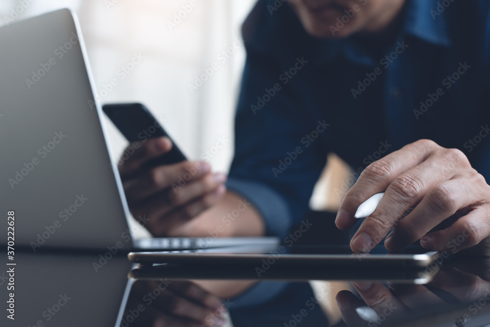 Poster multitasking business man working on digital tablet and laptop computer using mobile phone in office