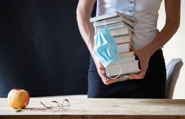 back to school during covid pandemic pile of books and medical mask