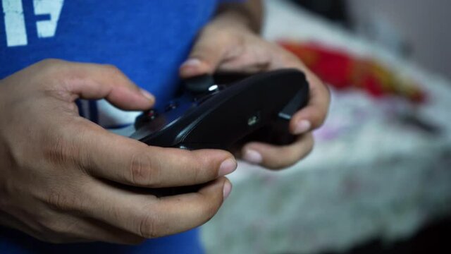 Guy in blue shirt playing on a video game console PC controller enjoying digital entertainment, e-sports or gaming while relaxing