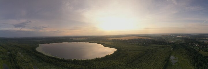 panoramic landscape of lake and forest around in summer at dawn filmed from a drone