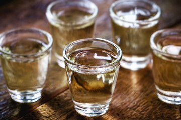 Glasses of Brazilian gold cachaça, distilled drink, on rustic wooden background.