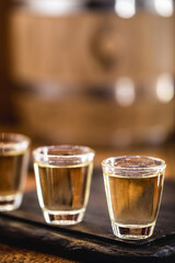Glasses of Brazilian gold cachaça, distilled drink, on rustic wooden background.