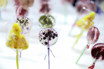 Transparent isomalt lollipops made manually with pieces of berries and fruit. Healthy and natural sweets made by hand for children are sold at a street fair or in pastry. Department or grocery store