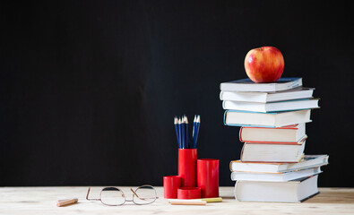 back to school concept pile of books against chalkboard