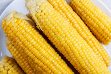 Boiled corn close up. Grains of sweet juicy corn. Cobs of boiled corn on a plate. Sweet corn. Healthy grains. Vegetarian food. A delicacy for children.