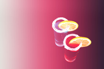 Mixed drinks in shot glasses with sliced lemon prepared by the bartender