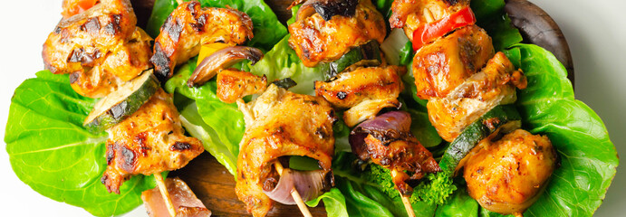 Grilled skewers with chicken, zucchini, mushrooms, peppers and onions served on iceberg lettuce