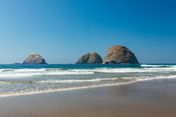 Sea Stack rocks sit just off a sandy beach near Oceanside Oregon