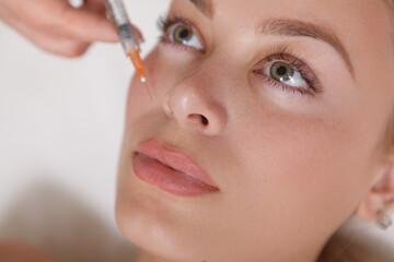 Close up top view shot of a beautiful woman getting face filler injections at cosmetology clinic