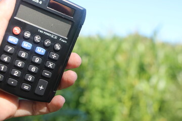 Farmer holding Calculator in hand calculate production field. Business concept.
