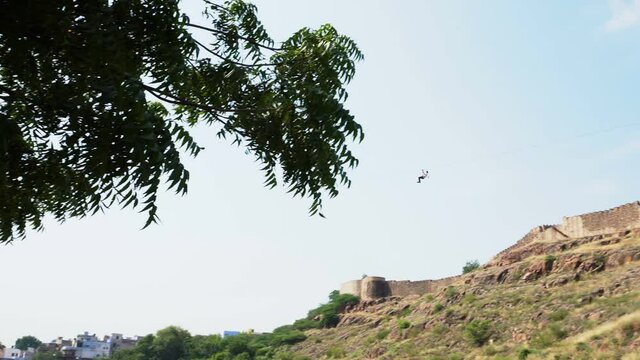 Tourist enjoying Mehrangarh fort zipline ride over the majestic Mehrangarh Fort. Vistas of the 'Blue City' of Jodhpur along with an aerial experience Rao Jodha Eco Park. Jodpur, Rajasthan, India.