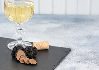 Black truffles and slices with white wine on black stone background