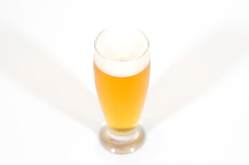 A glass of beer filled with foam centered in the image with a white background.