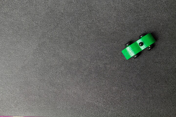 Green old wooden car toy top view on grey stone background. Car rental