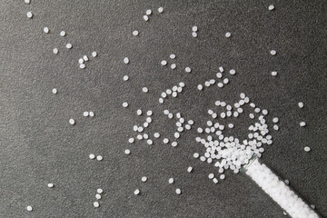 Plastic pallets. White Polyethylene granules spilled out of a laboratory test tube on a stone background. Plastic Raw material .High Density Polyethylene.