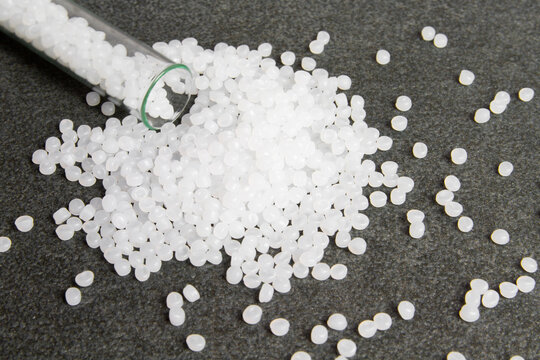 Plastic pallets. White Polyethylene granules on a stone background. Plastic Raw material .High Density Polyethylene.