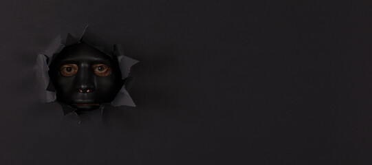 a man in a black mask in a black paper hole