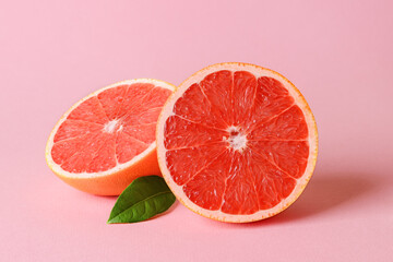 Two halves of fresh ripe juicy grapefruit and leaf on a pink background. Vegetarian, raw food diet...