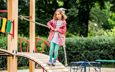 Fototapeta premium Little girl climbing rope on playground