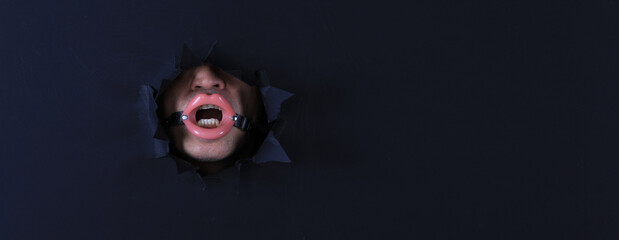 man in fetish mask in black paper hole